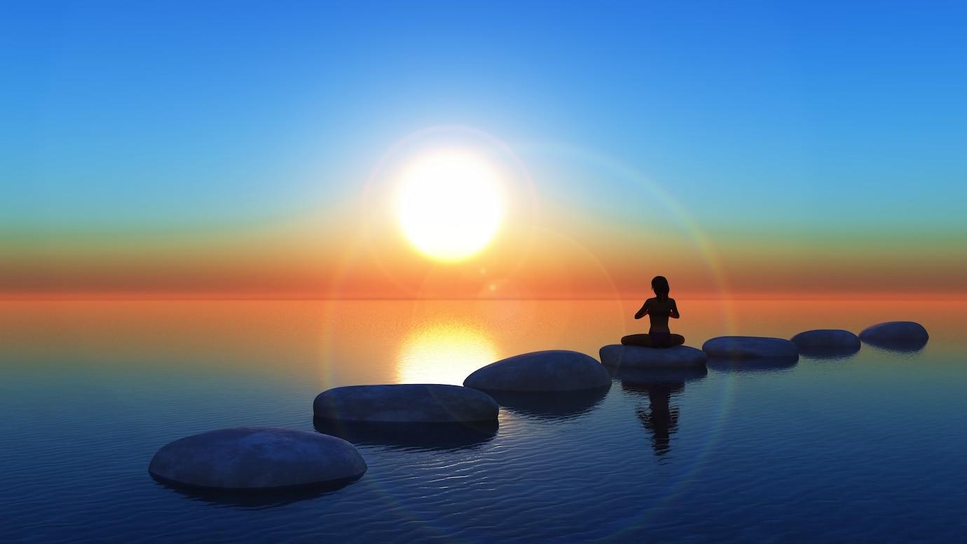 A person sitting on stepping stones in the water.